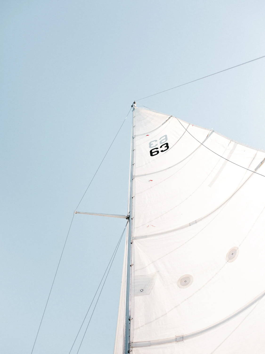 The main sail of a sailboat set against a blue clear sky
