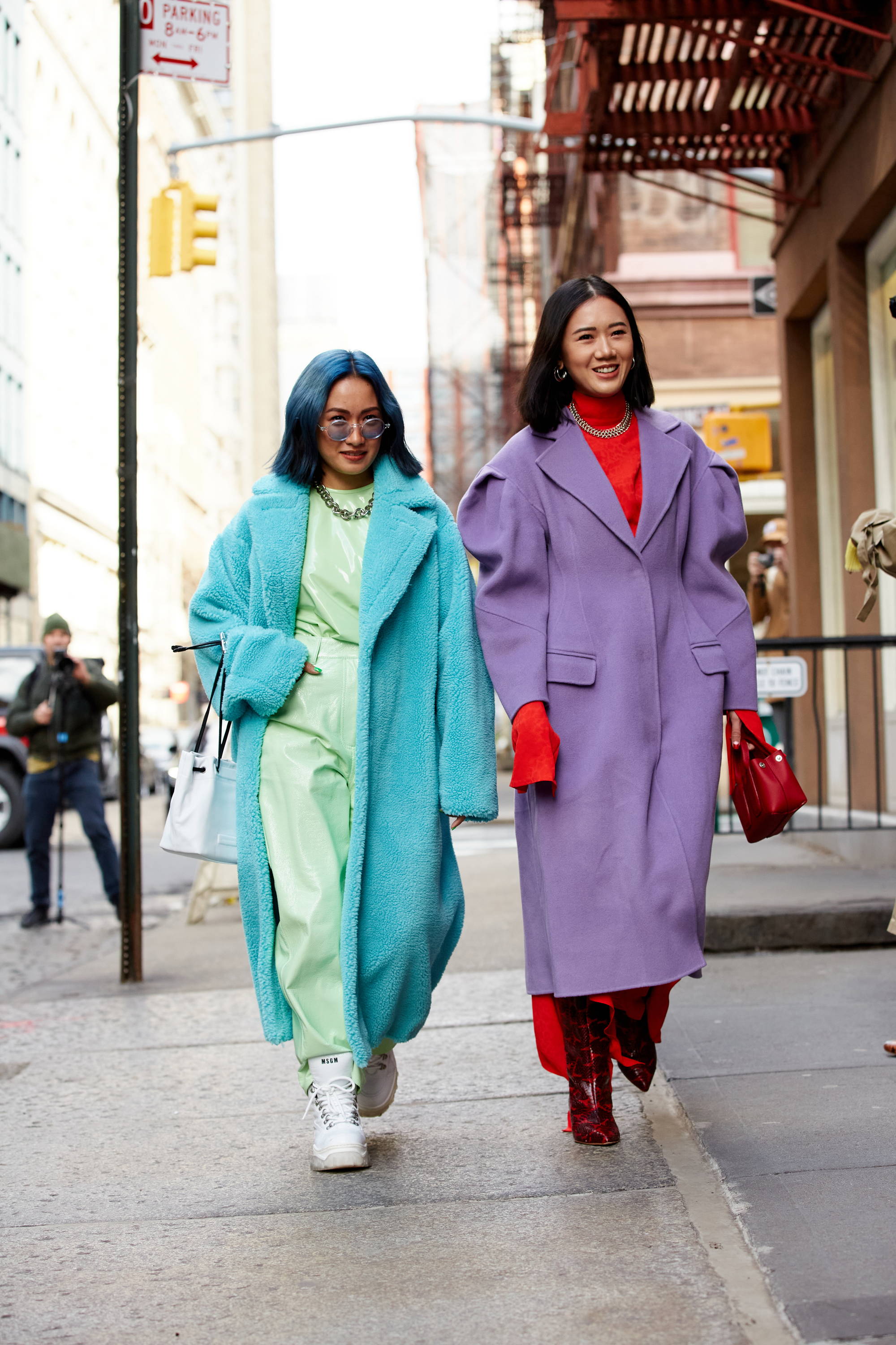Two women in colorful coats walking on the street.