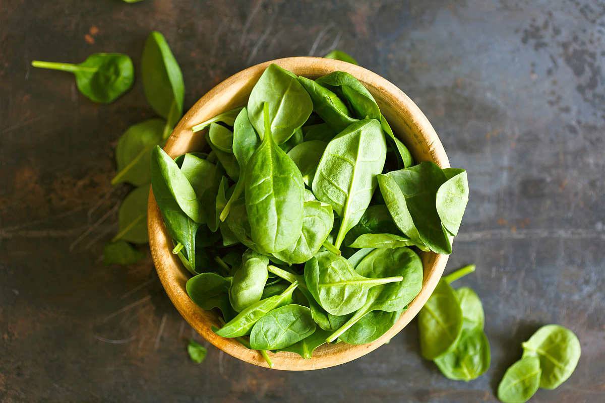 Spinach on wooden bowl | Surprising Differences of Whole Food Vitamins Vs. Synthetic Vitamins | synthetic vs natural vitamins