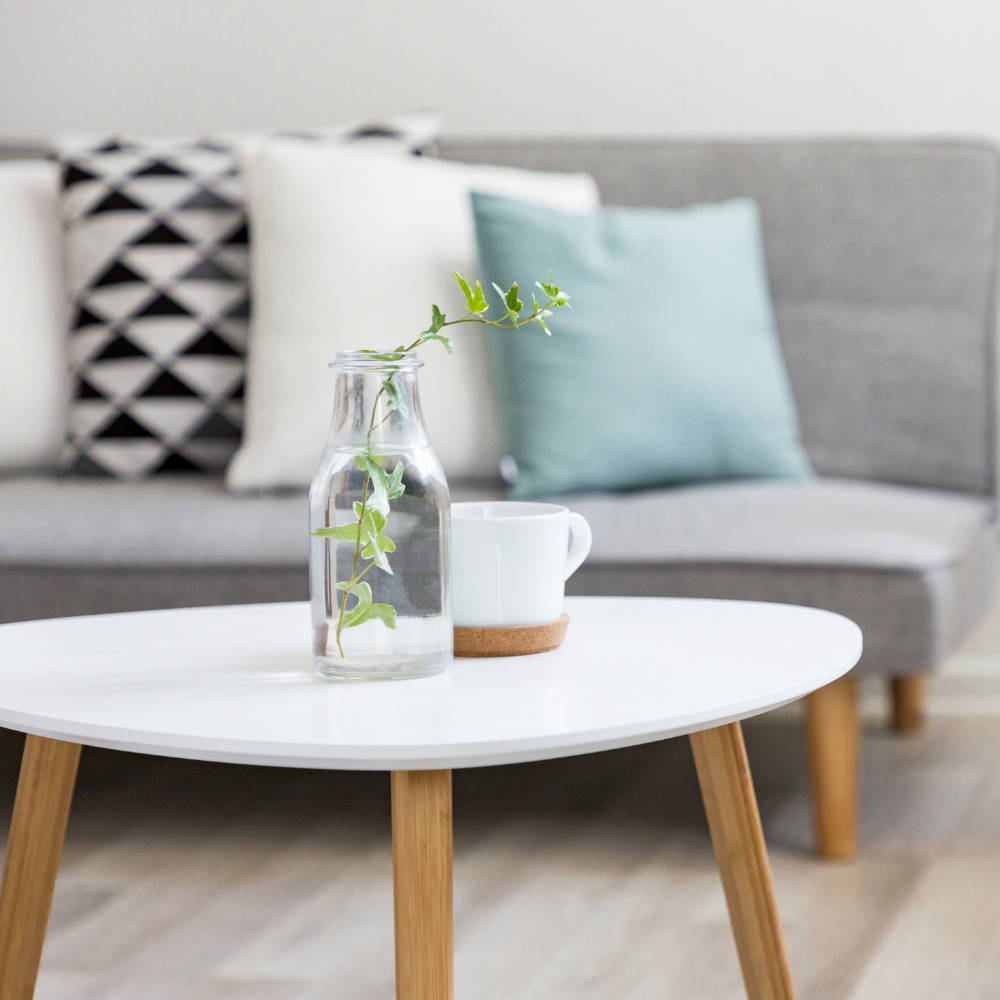 An artificial plant inside a clear vase on a coffee table