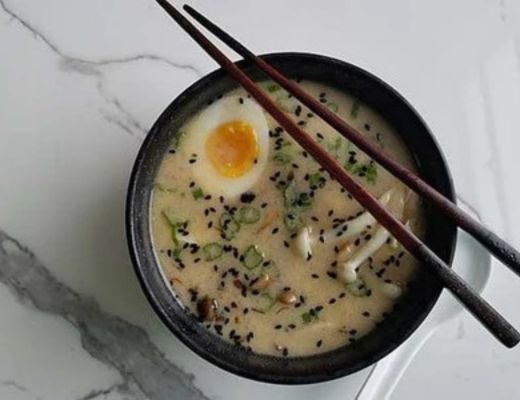 A bowl of ramen with an egg and chopsticks.