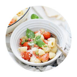 Shellbows pasta, tomatoes and peas in a buttery parmesan sauce served in a bowl