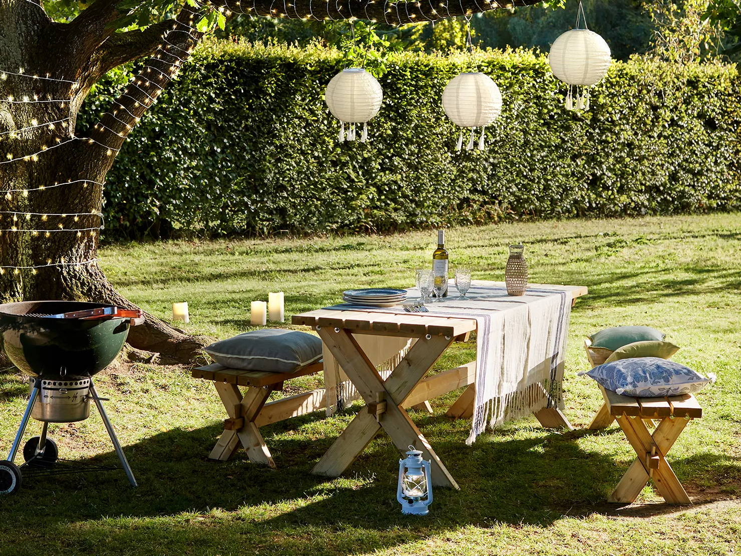 Garden setting with picnic bench and BBQ featuring candles and lanterns