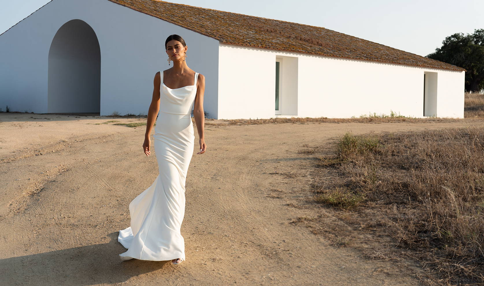 Landscape image of bride outside house in Portgual wearing the Grace wedding gown