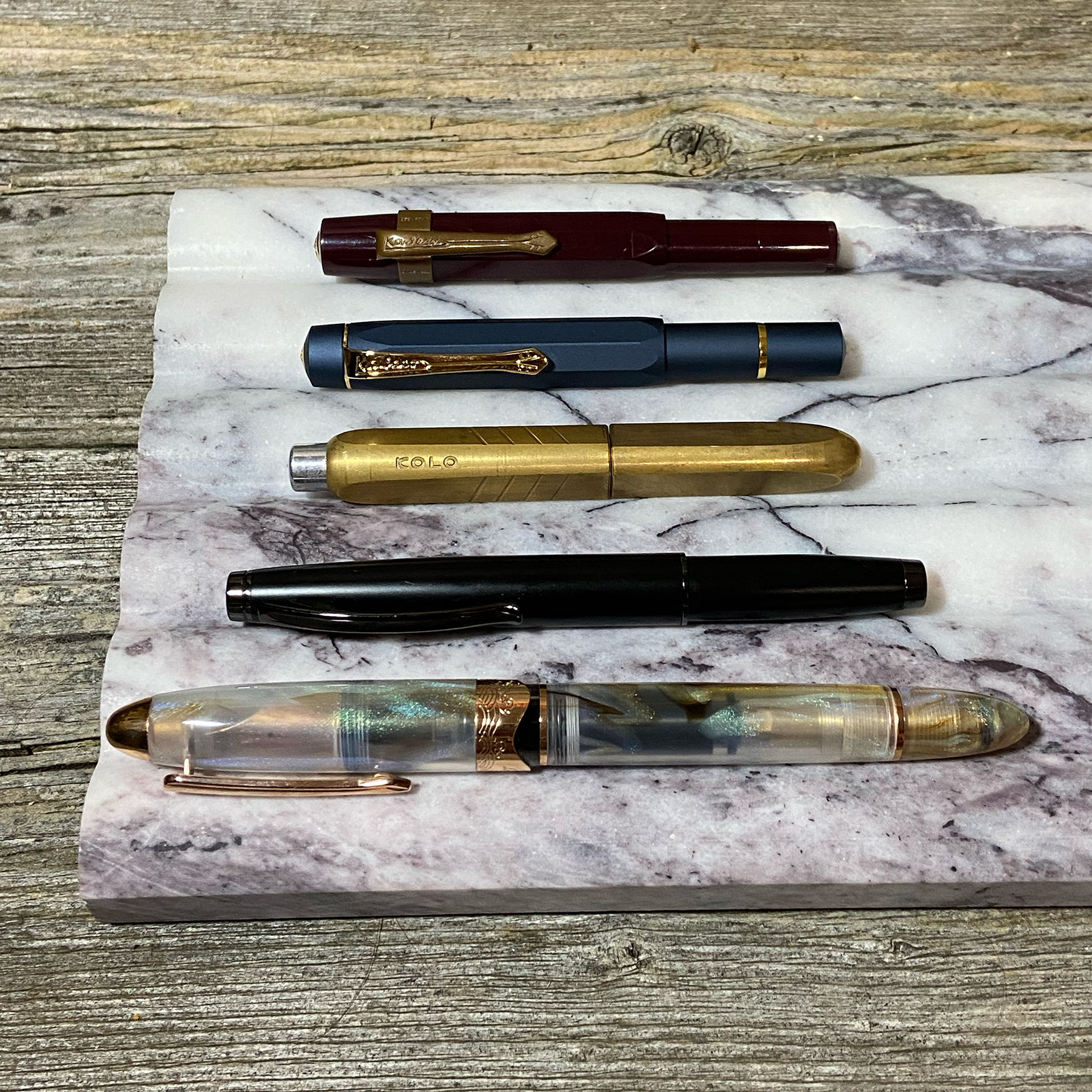 Alexandra's selection of currently inked fountain pens, featuring a Kaweco Sport, Kaweco Piston Sport, a Monteverde Dakota, a Kolo Tino Brass, and a Nahvalur Horizon fountain pen