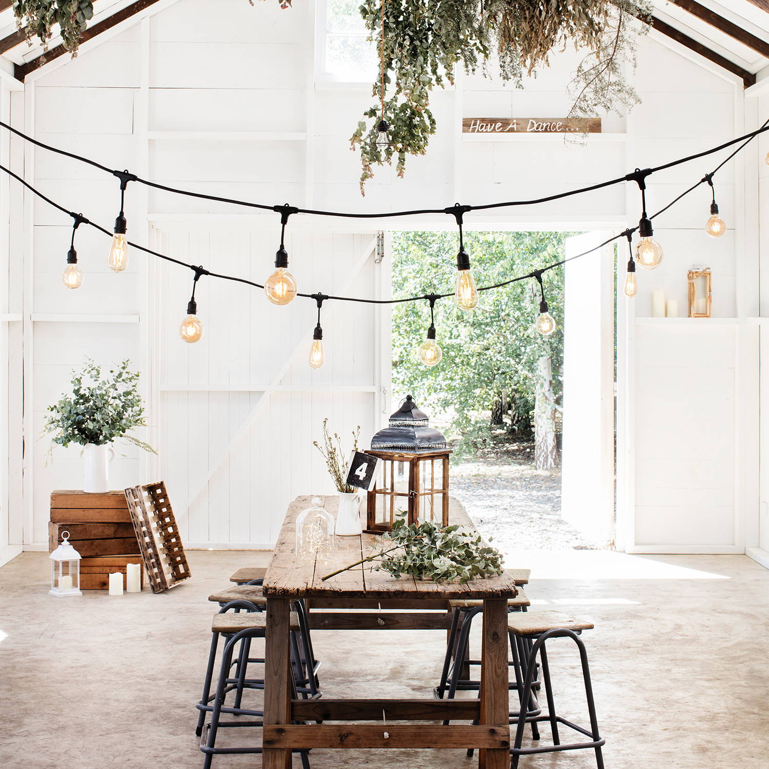 An indoor barn setting with Ingenious Connect festoon lights hanging over a wooden table.