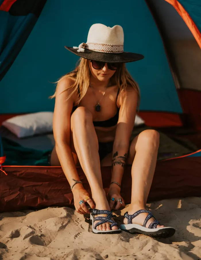 woman adjusting vegan sandals in tent 
