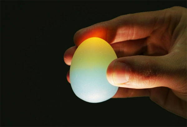 An oil-polished Sunset Egg, lit from below, shows both blue sky and yellow sun.