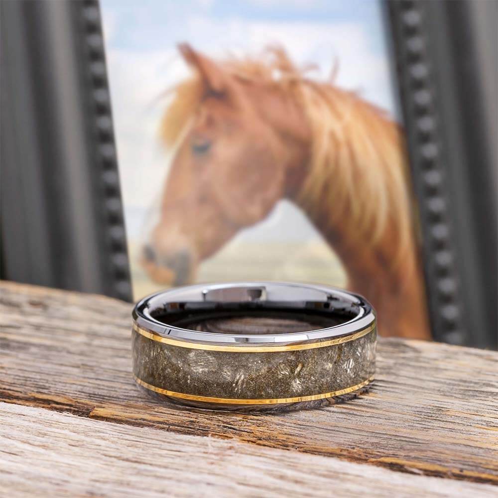 A memorial ring on a wooden surface with a horse portrait in the background.