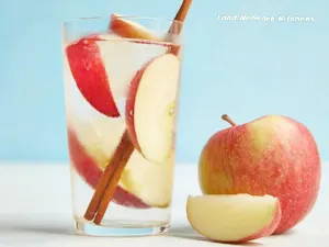 Glass of water with apple slices and cinnamon sticks