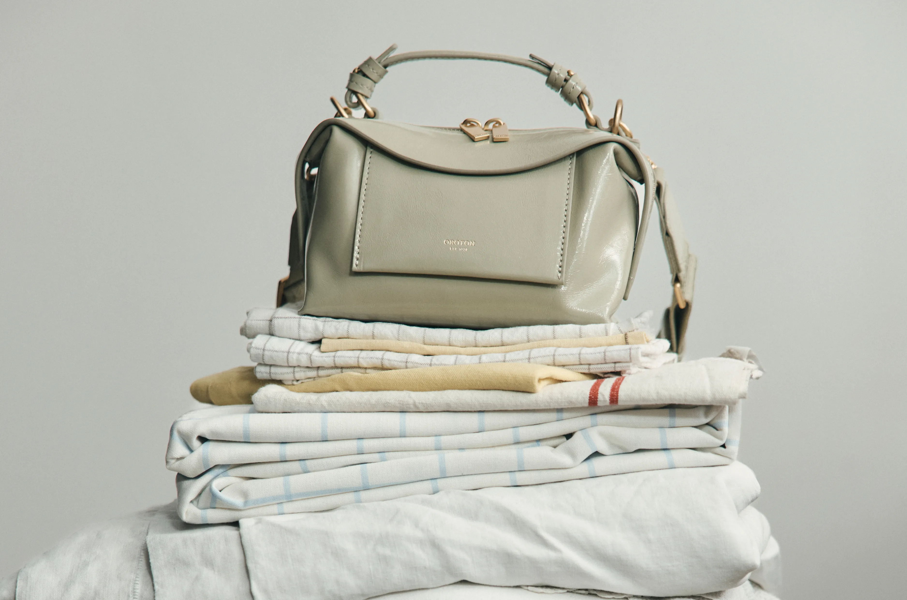 A stylish handbag on a stack of neatly folded linens.