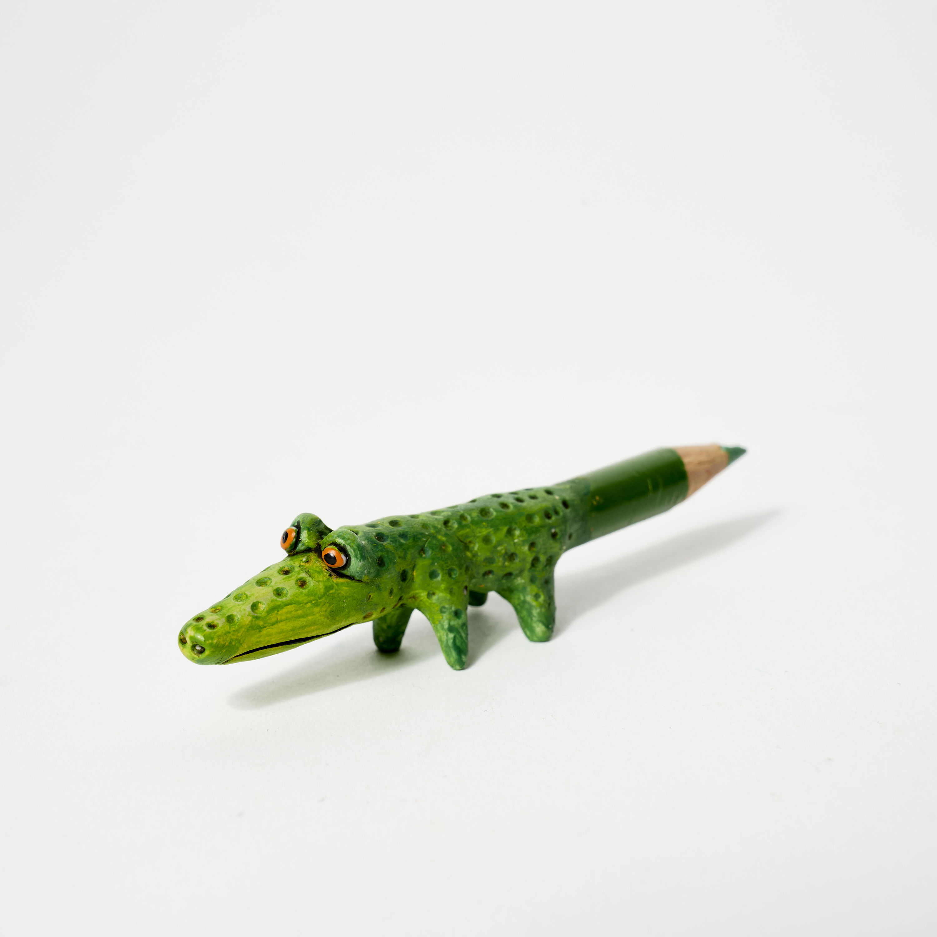 A green crocodile-shaped pencil with a colored tip.