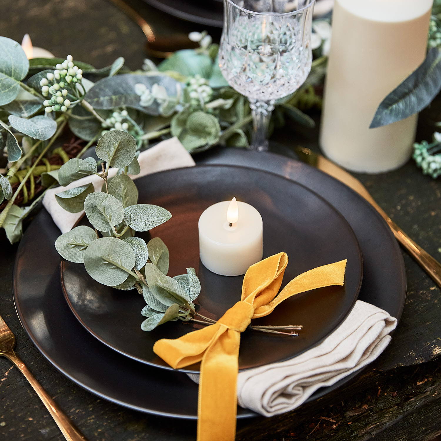 Wedding table place setting with votive candle and foliage tied with yellow ribbon on plate