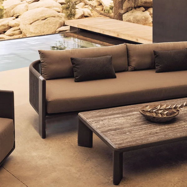 Outdoor lounge furniture with deep cushioned seating and a low coffee table arranged beside a pool for a backyard entertaining layout.