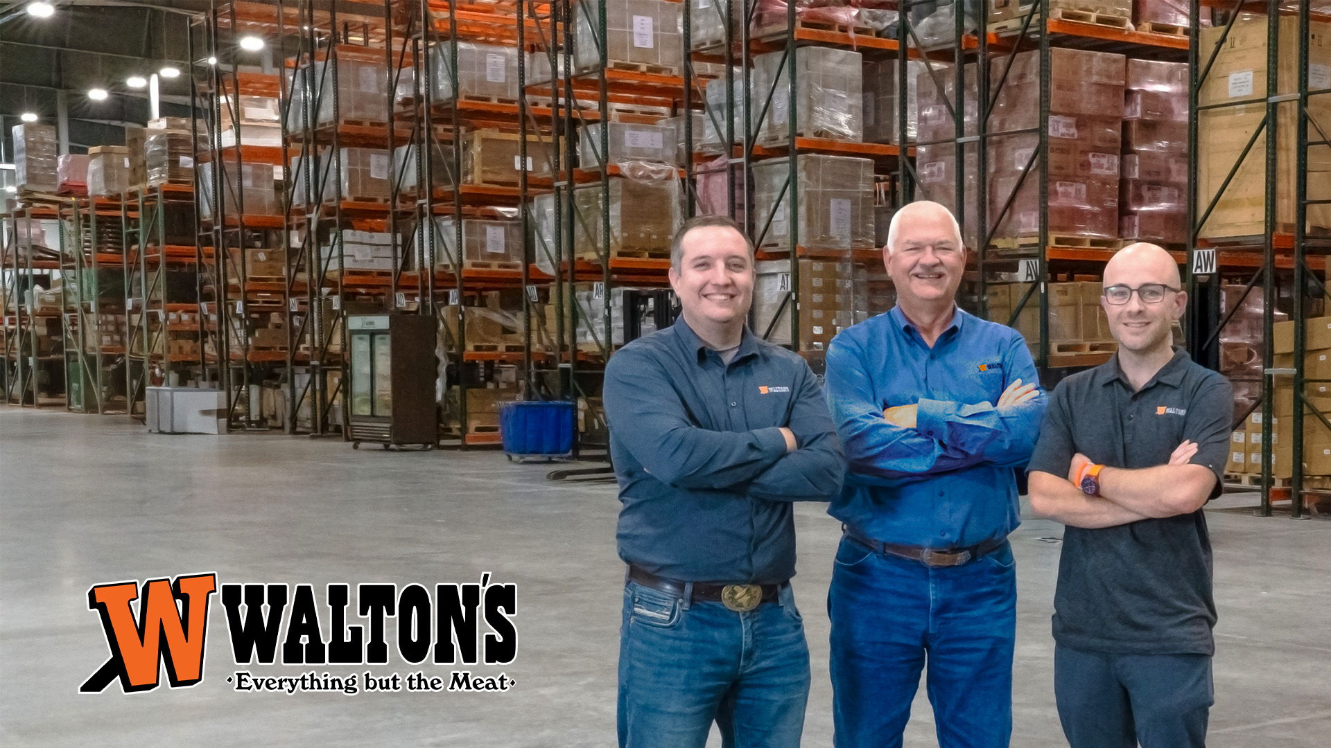 Walton's owners standing in the warehouse with shelves of products. Waltons logo visible.