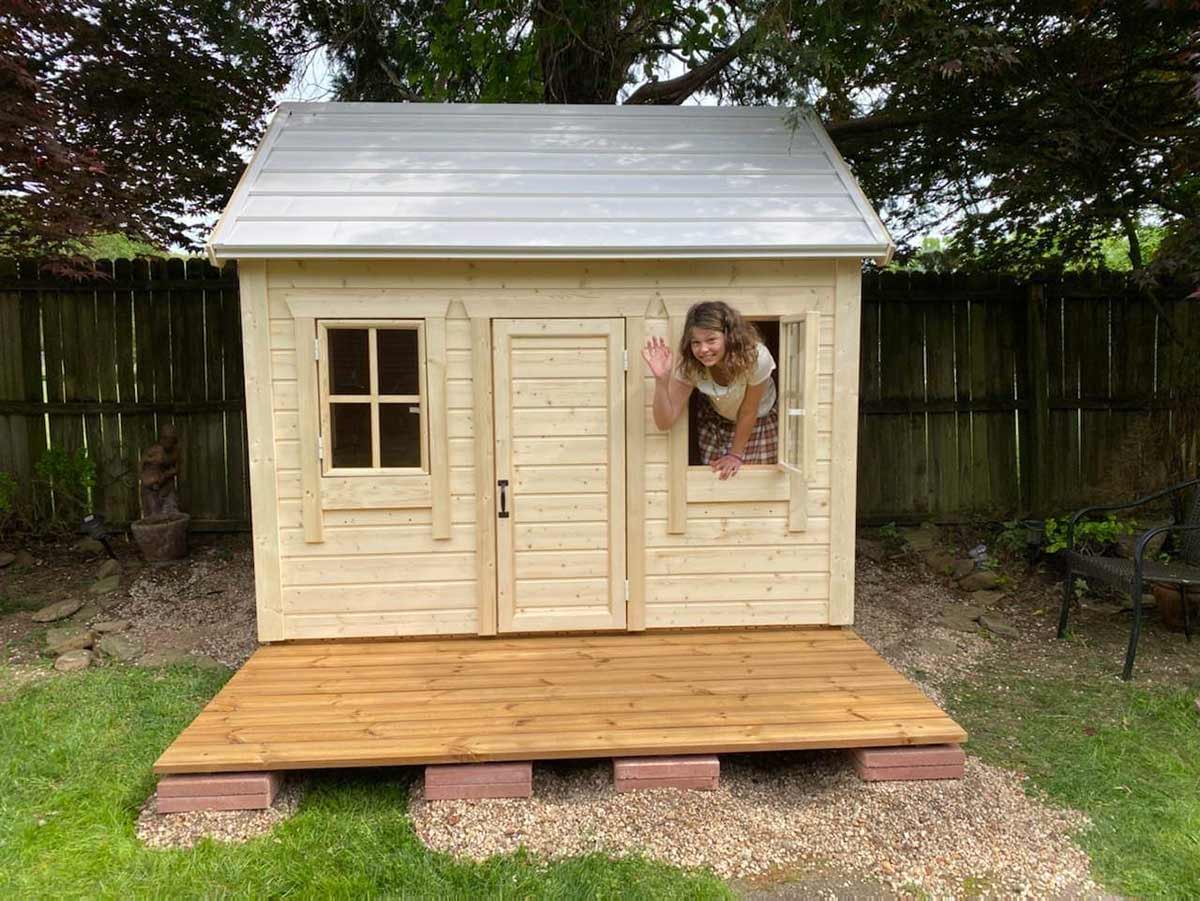 Outdoor Playhouse Natural Wonder with white metal roof and wooden terrace in a backyard by WholeWoodPlayhouses