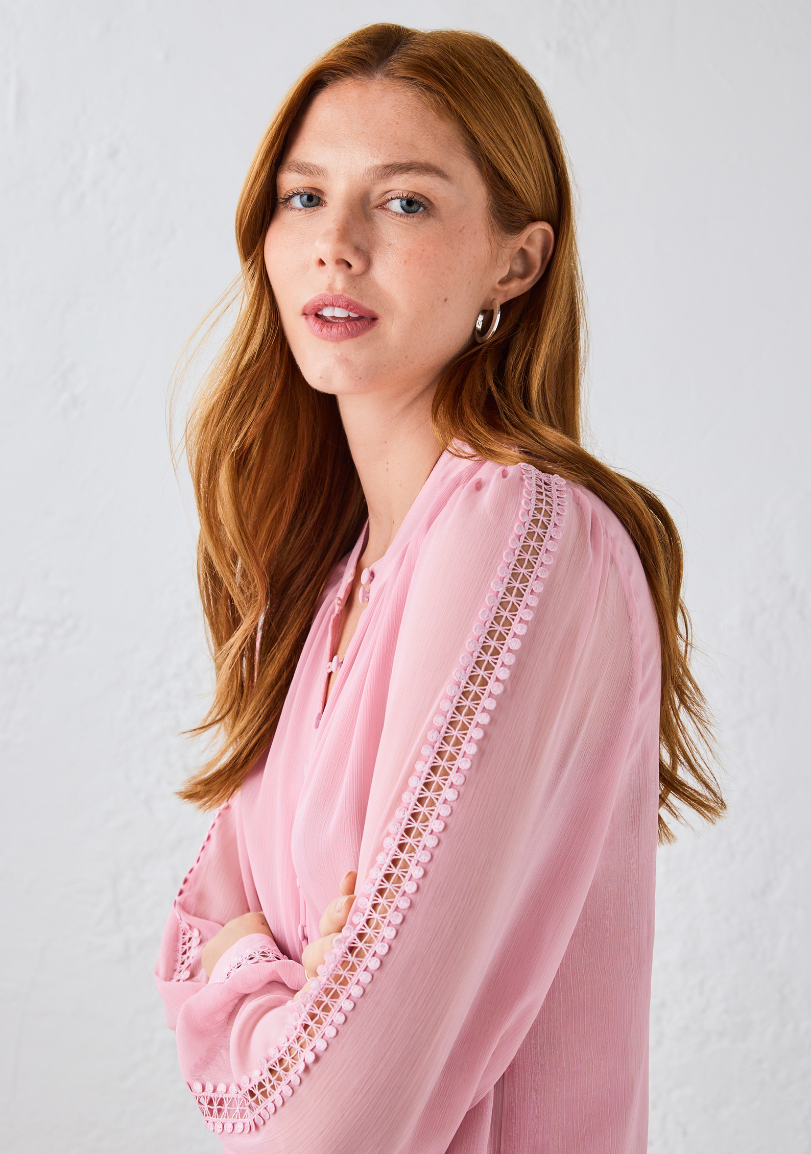 Woman with long hair wearing a pink blouse against a light background.