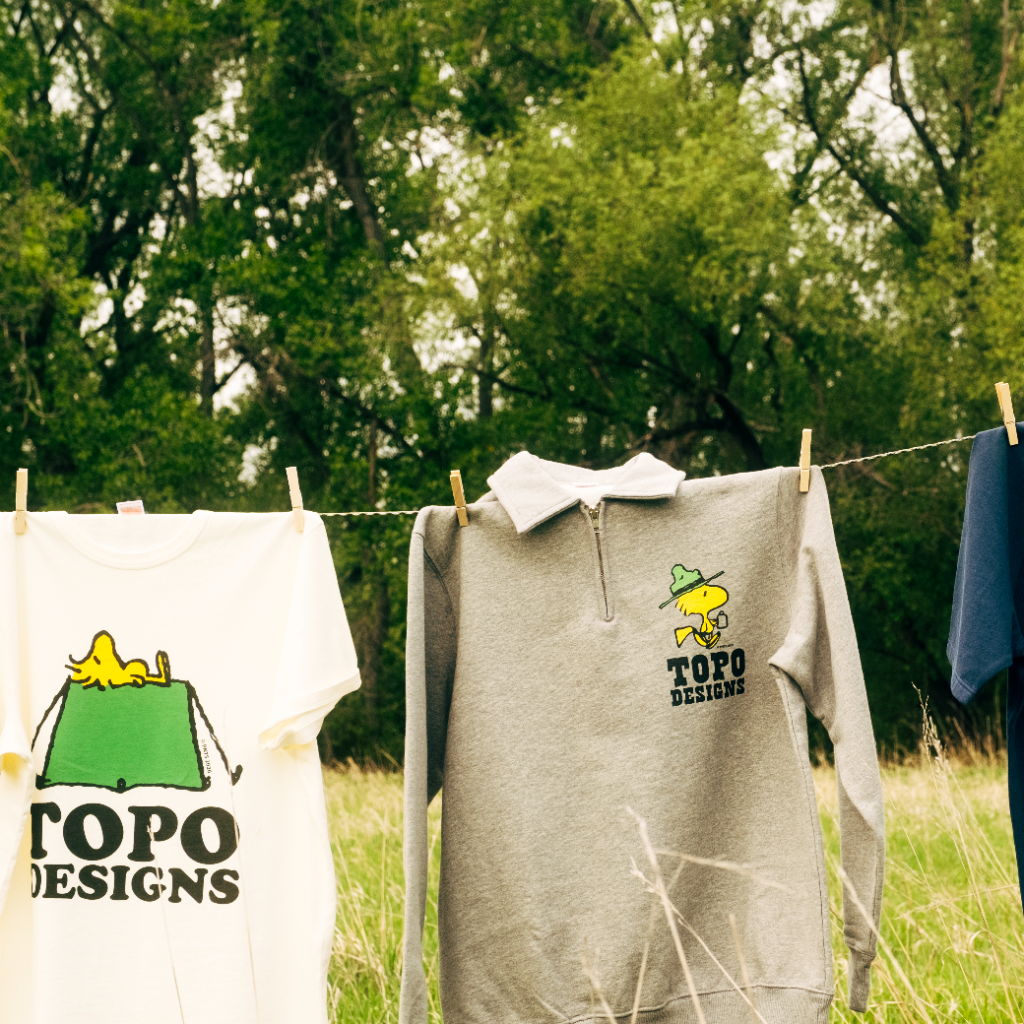 T-shirts and polo shirts hanging on a clothesline in a grassy area.