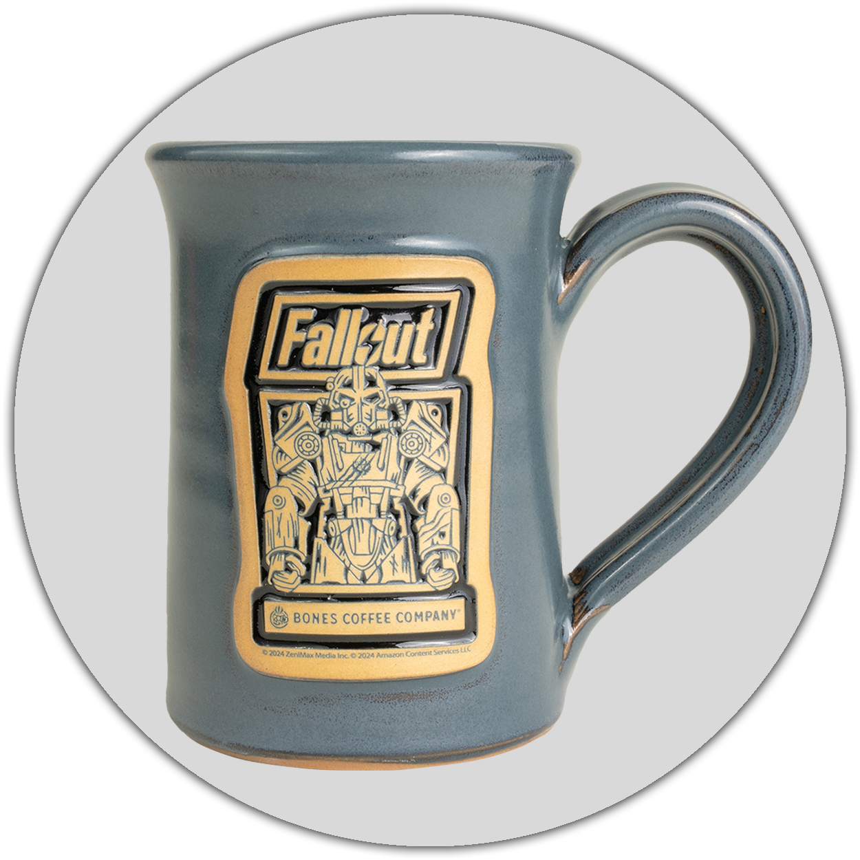 The front of the Bones Coffee Company Maximilius hand thrown mug with the Valiant Vanilla art on the golden medallion. It is inspired by Zenimax and Amazon’s Fallout show. The mug is gray colored. A light gray circle is behind it.