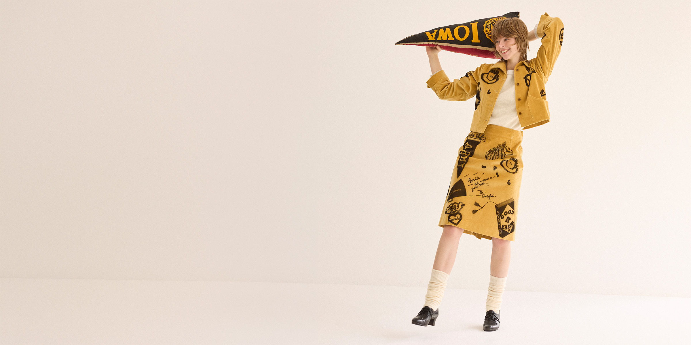 Person in yellow outfit holding a pennant, posing against a plain background.