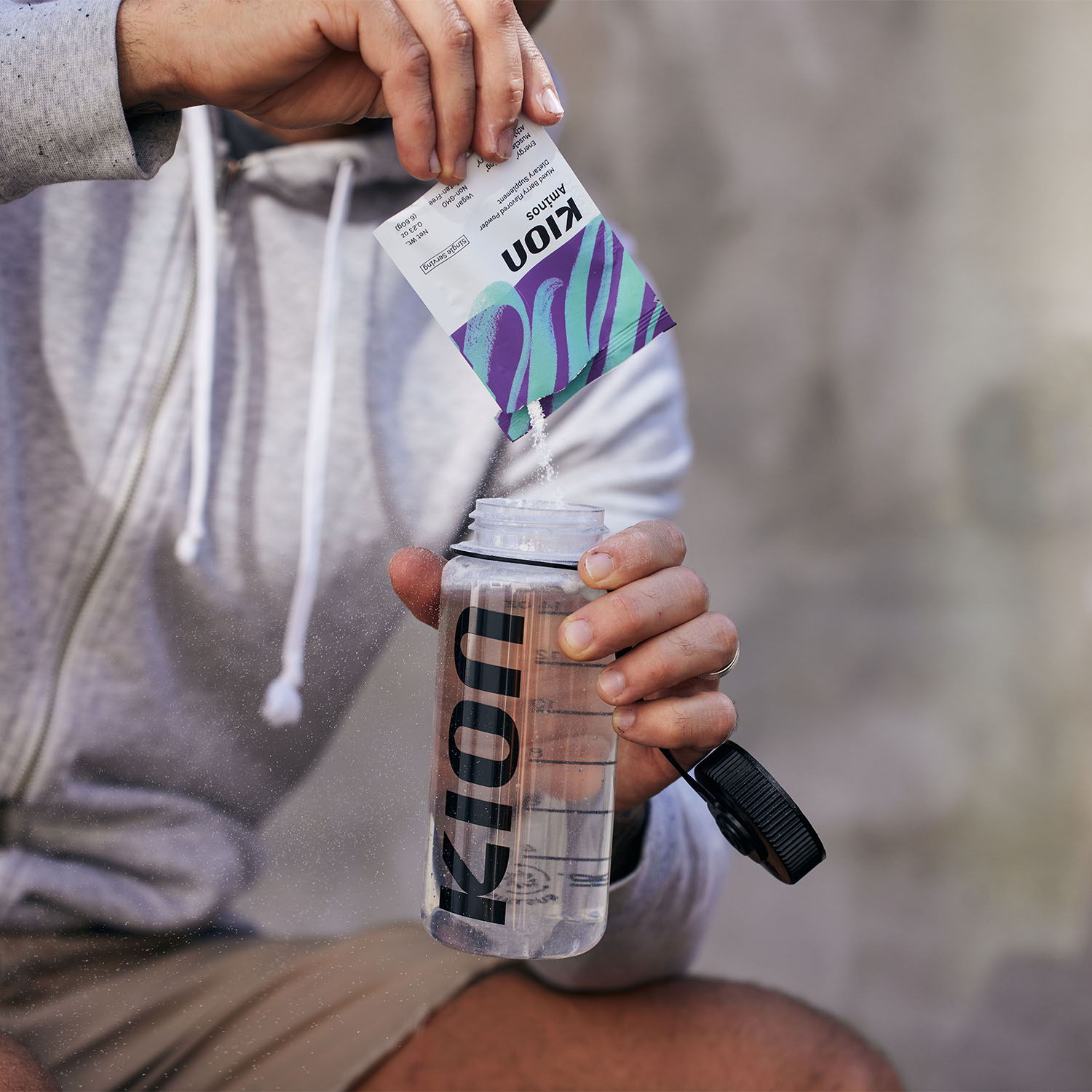 Person holding a water bottle while unwrapping a product package.