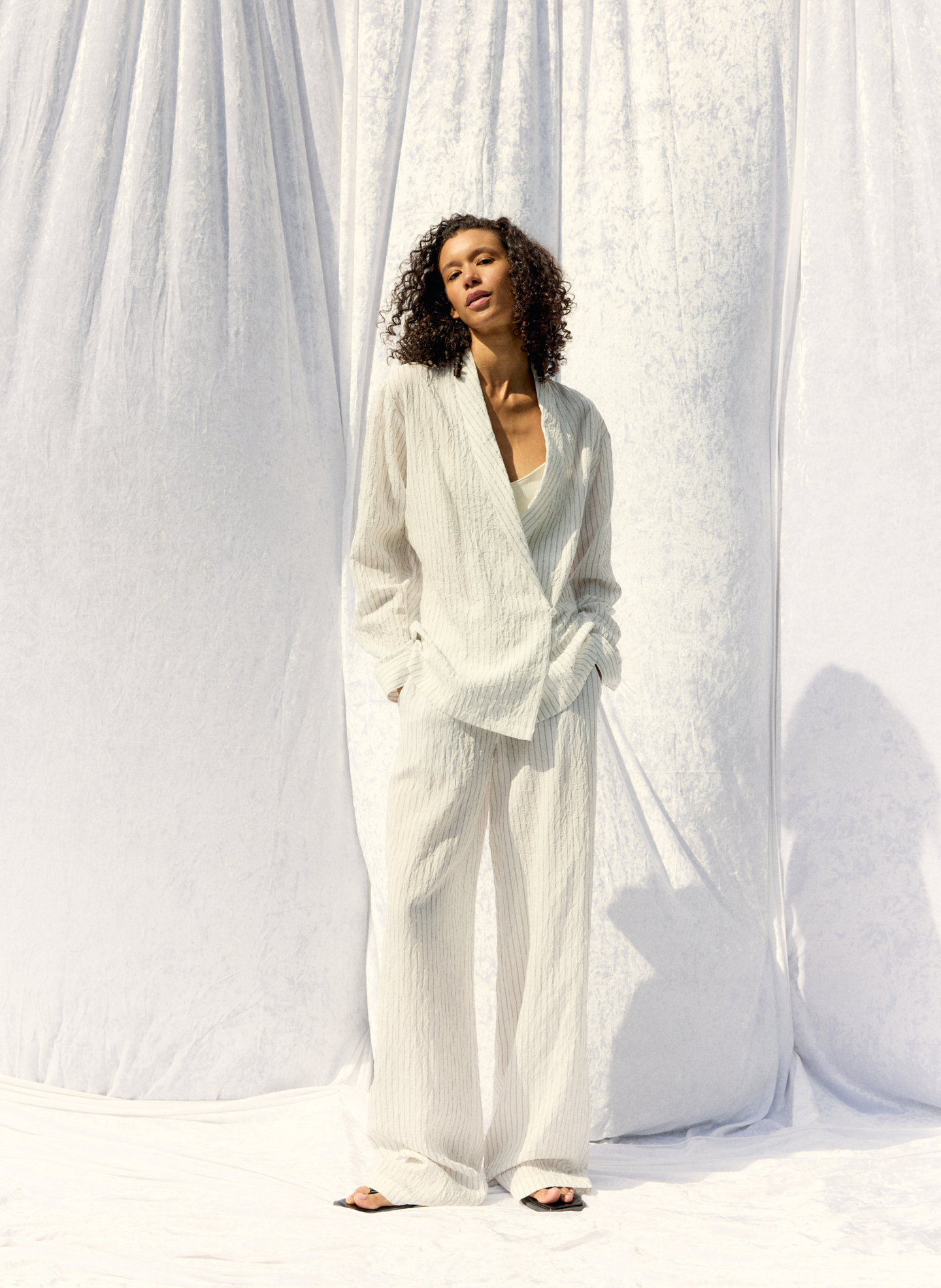 Model in light-colored outfit against a white backdrop.