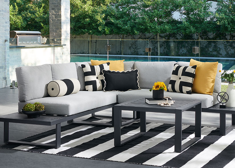 Outdoor seating area with cushions, black and white rug, and coffee tables.