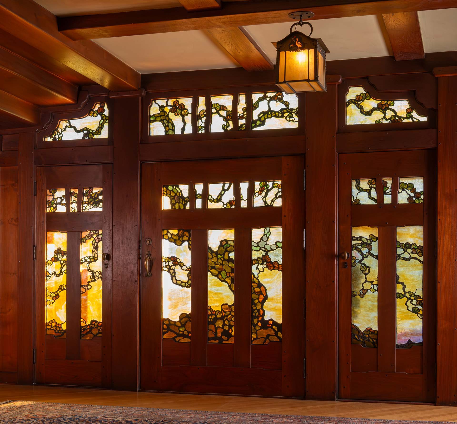 The stained glass front door of the Gamble House seen from the interior. It features a sprawling tree design across many panels.