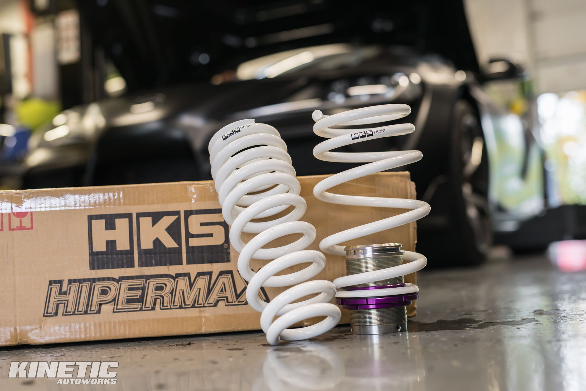 HKS Hipermax suspension components with a performance car inside the Kinetic shop