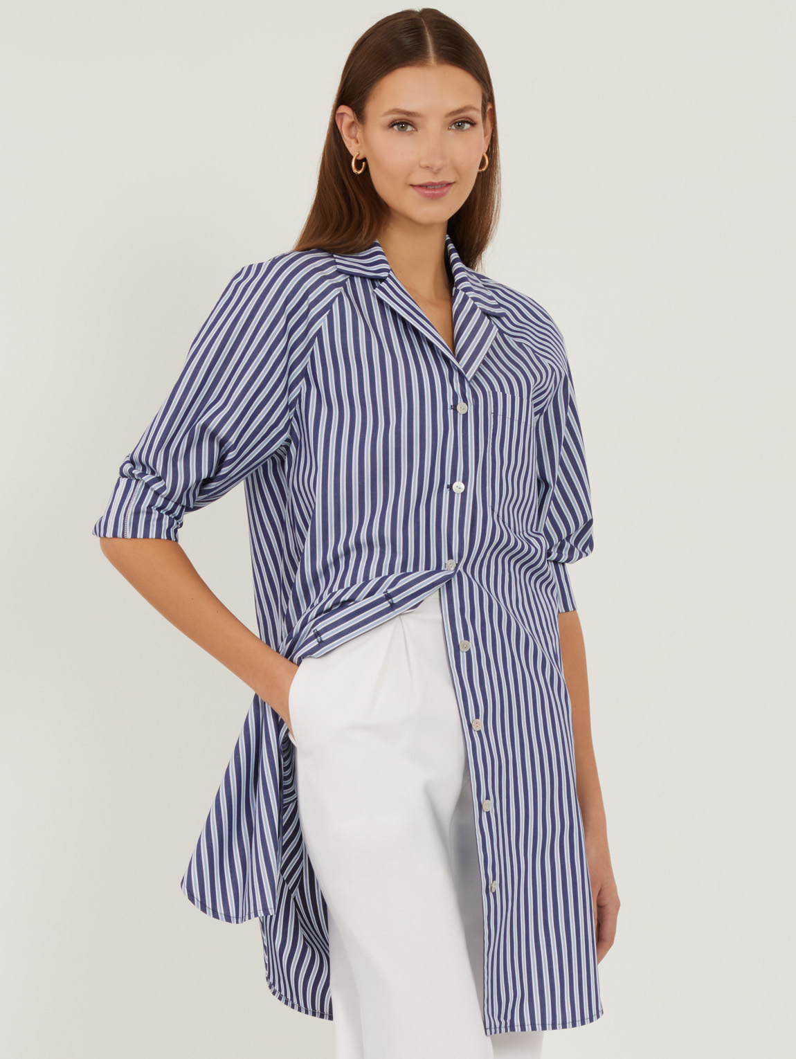 Woman wearing a blue and white striped shirt with white pants.