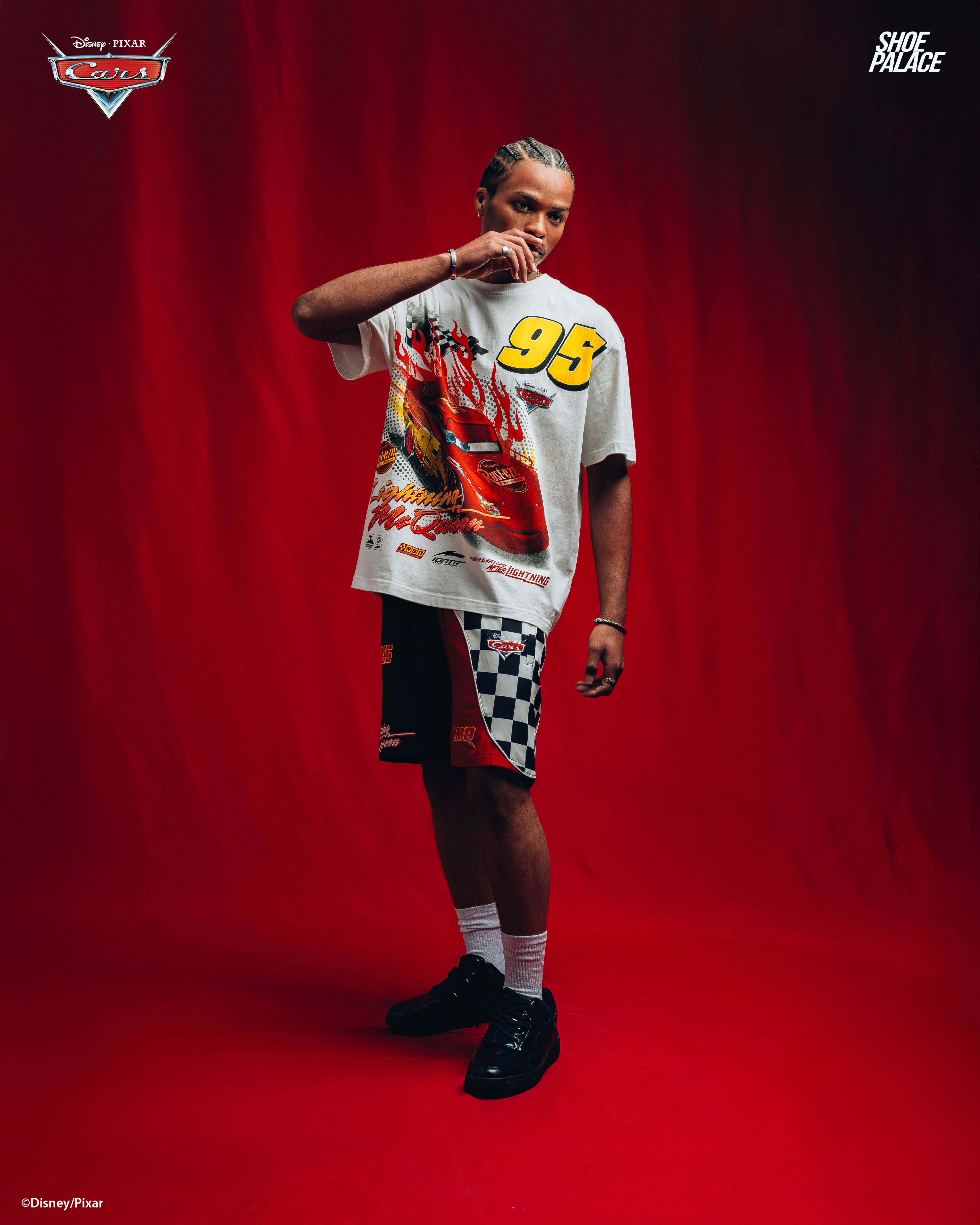 Person in graphic t-shirt and shorts against a red background.