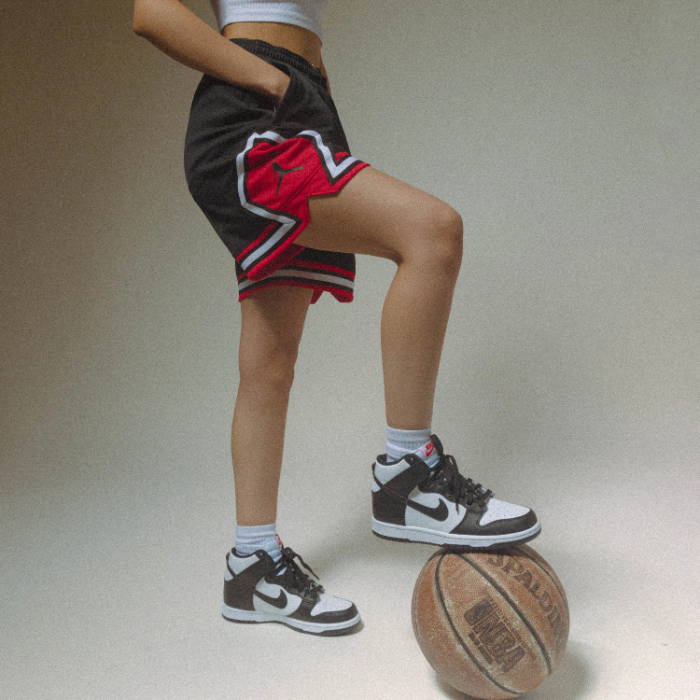 woman with foot on basketball wearing jordan jersey and shorts