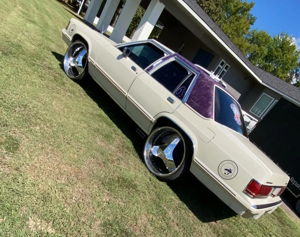 White Mercury Grand Marquis side and rear view on large chrome wheels