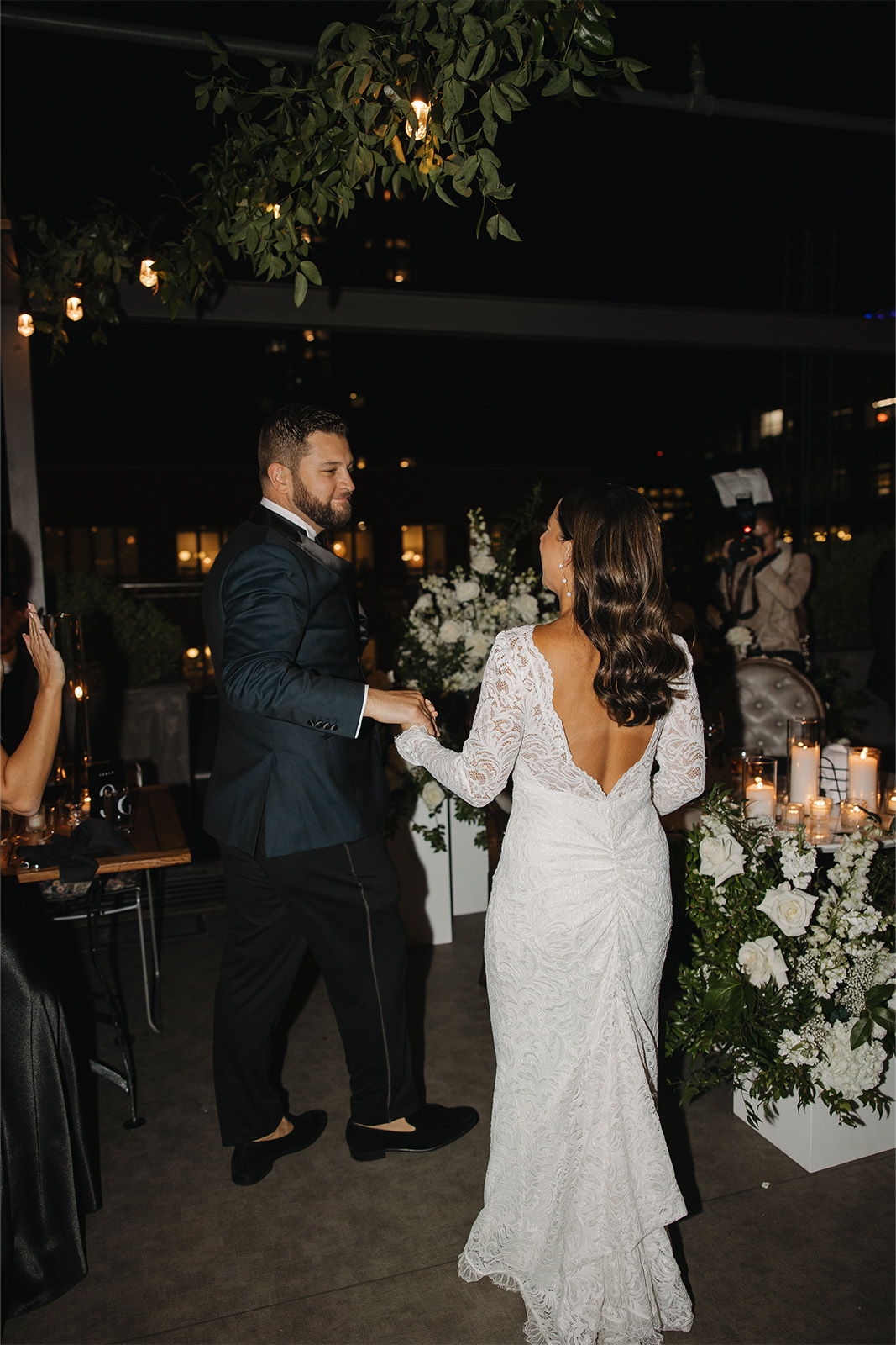 A couple dancing at a wedding reception, surrounded by flowers and candles.
