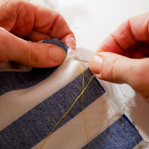 sewing basting stitches with needle and contrasting yellow thread