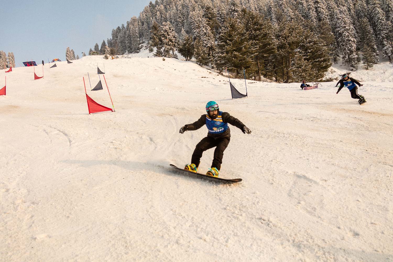 Snowboarder navigating a course with flags in a snowy landscape.