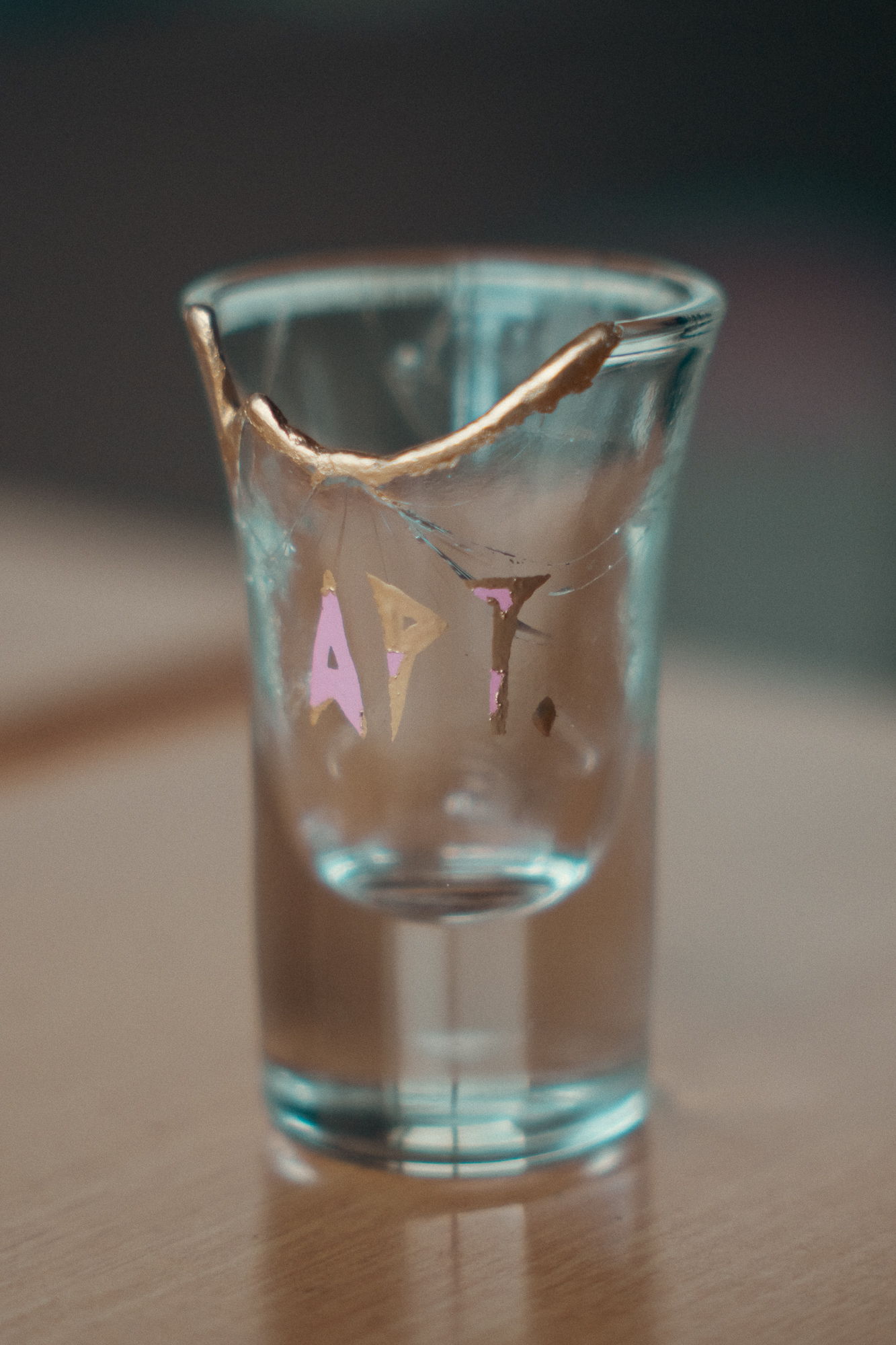 A broken shot glass with the letters 