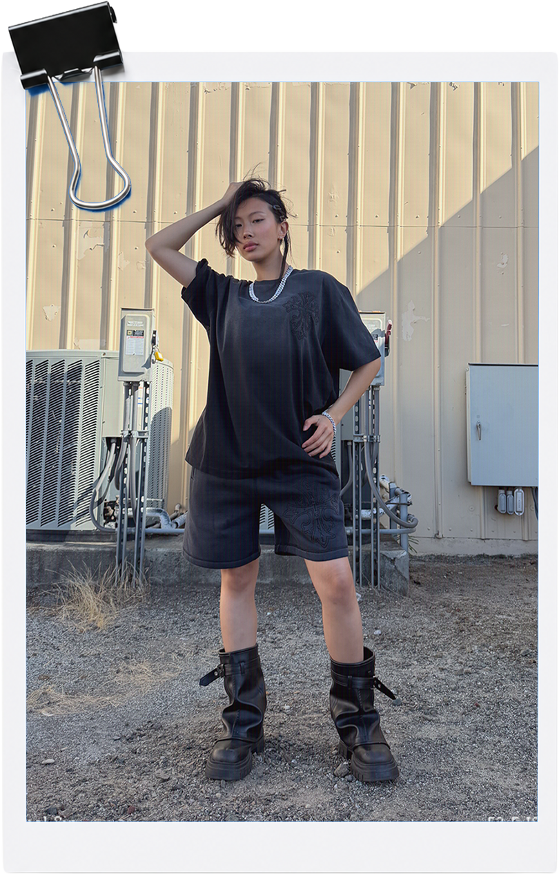 Person in casual outfit standing confidently against a wall.