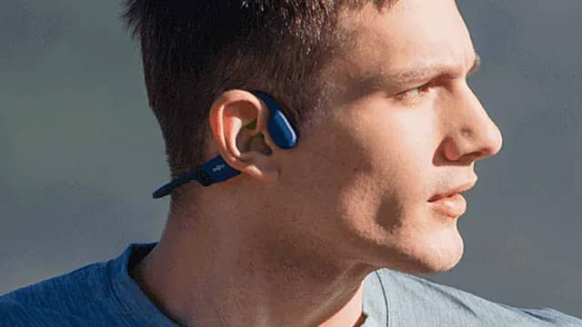 Profile of a man wearing wireless earbuds outdoors.