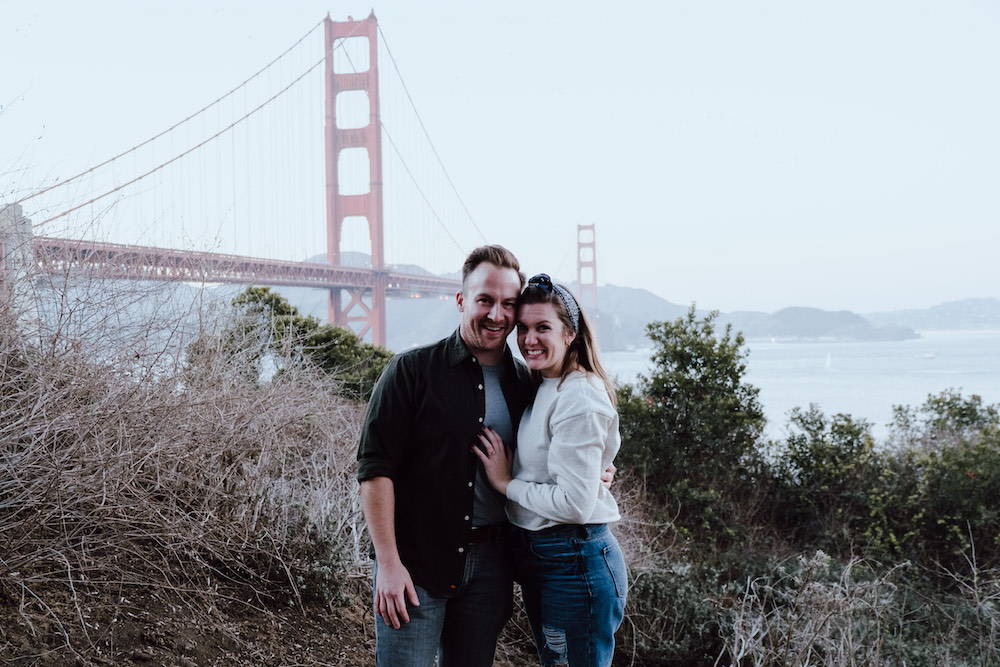 happy couple posing by golden gate bridge
