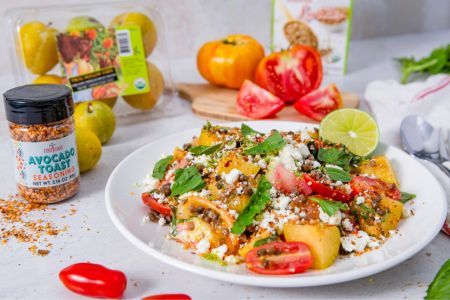 A colorful salad with tomatoes, greens, and spices on a white plate.