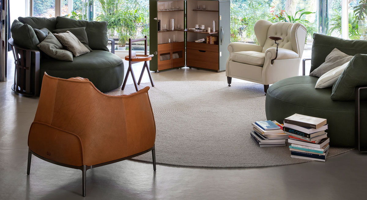 A cozy living room with Archibald Armchair by Poltrona Frau and stacked books.
