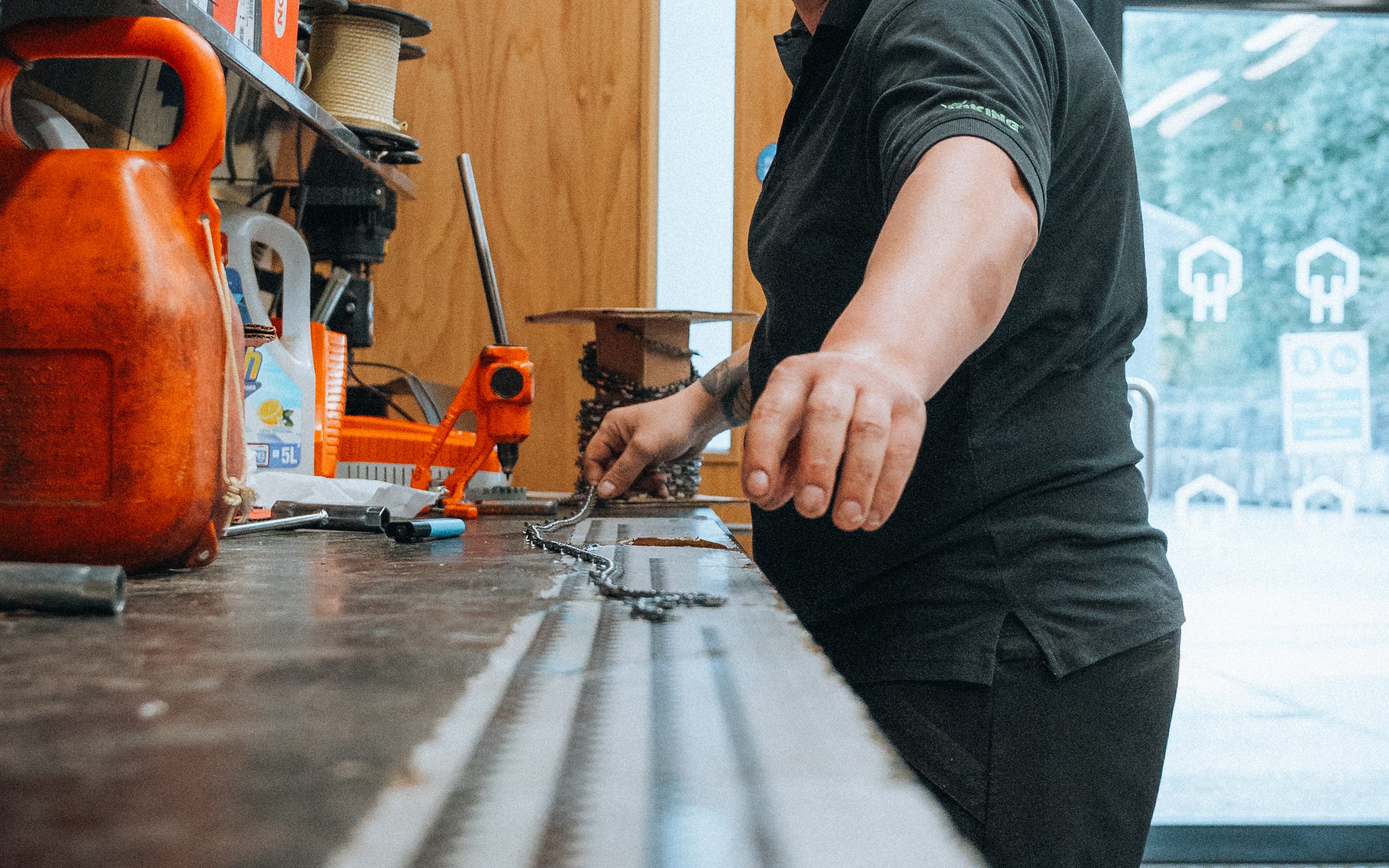 Person working at a workshop table with tools and equipment.