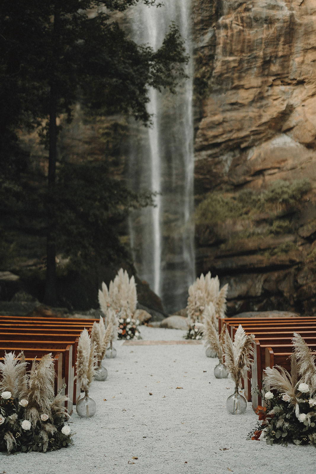 Outdoor wedding ceremony with wooden pews and floral arrangement