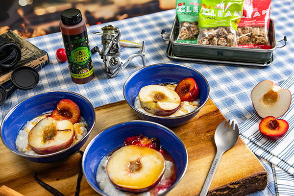 Three bowls of oatmeal topped with sliced peaches on a picnic table.