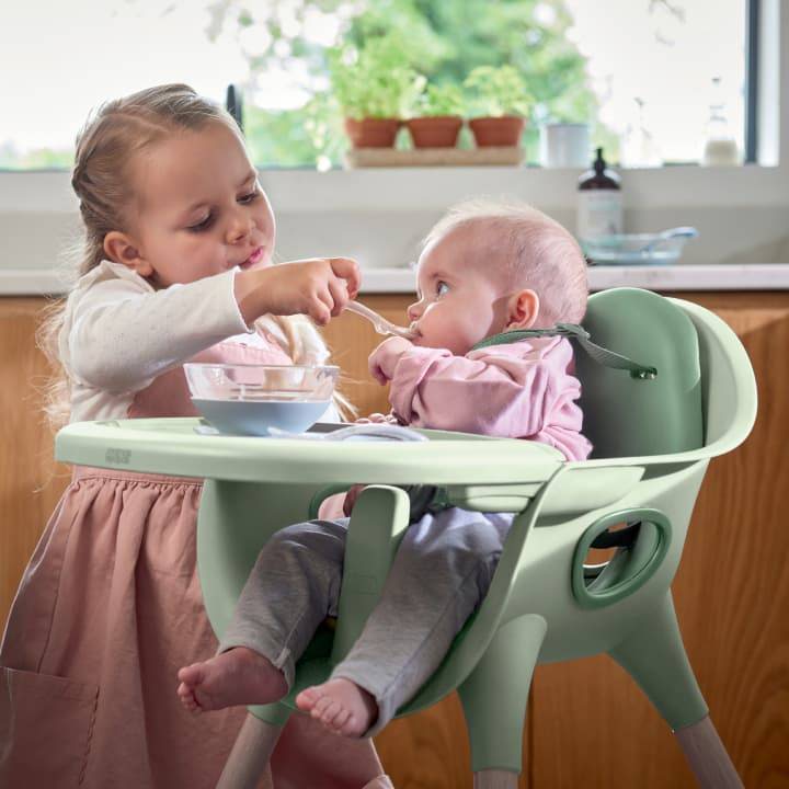 Little girl feeding baby in a Juice highchair
