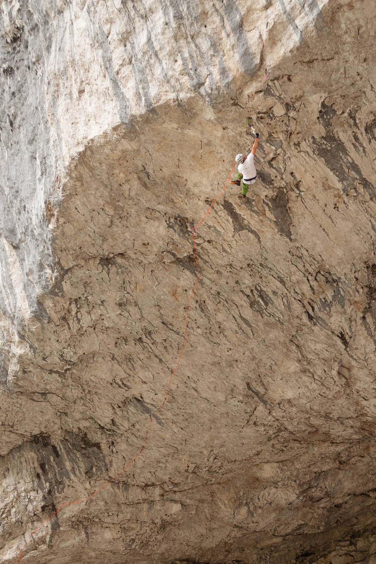 Wide shot of climber rock climbing among tan rocks with orange rope