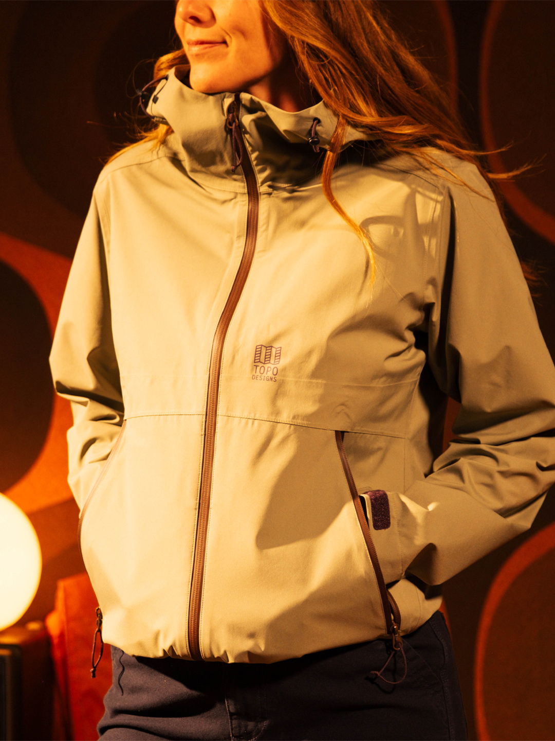 Woman wearing a light-colored jacket, standing in a stylish indoor setting.