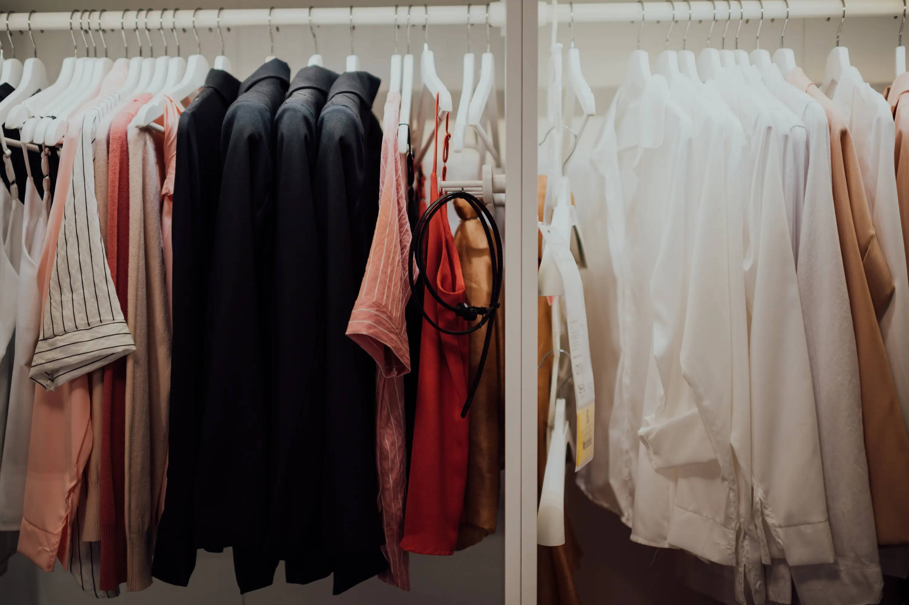 Clothes on a rack in a closet.