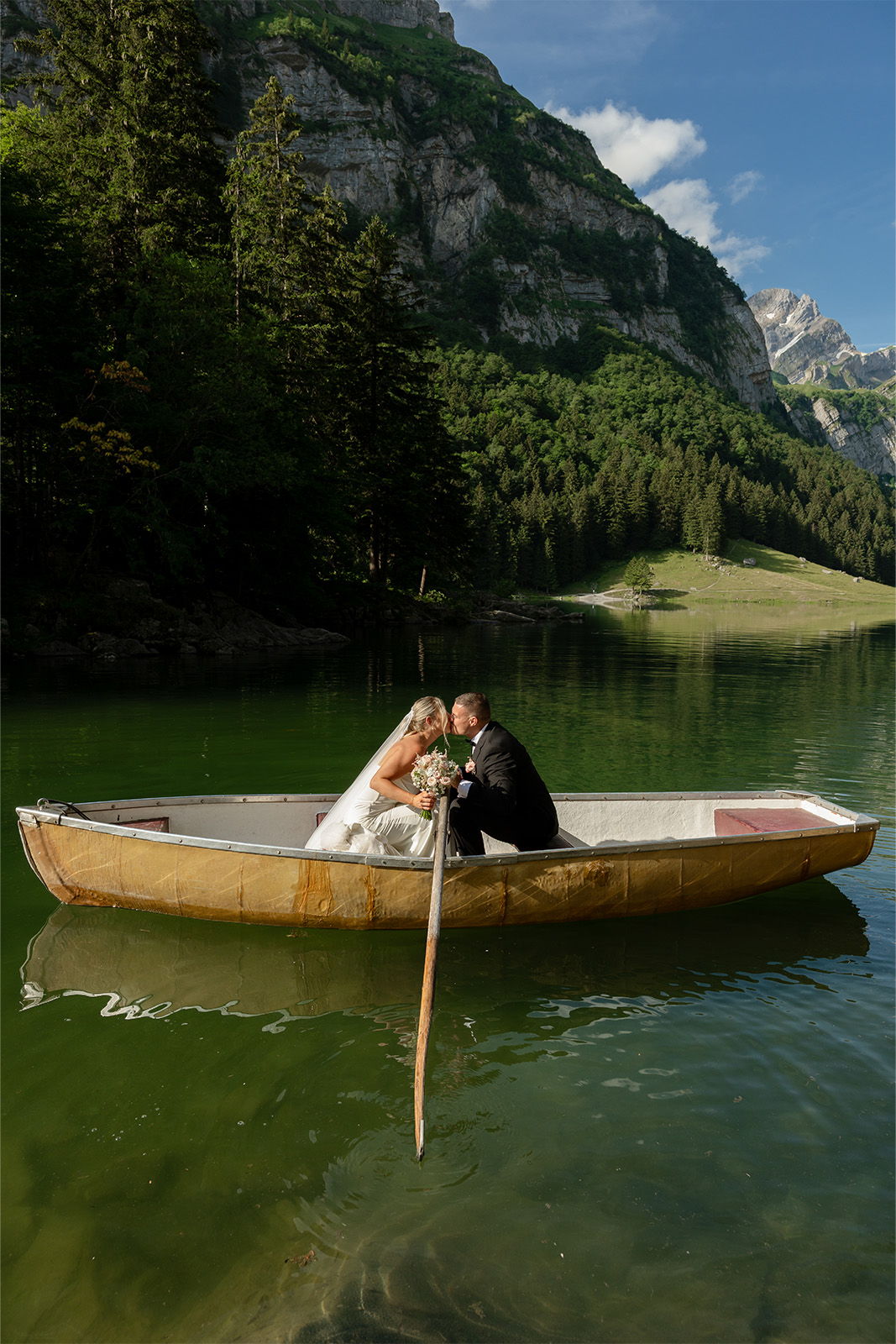 Couple in a boat on a serene lake surrounded by mountains.